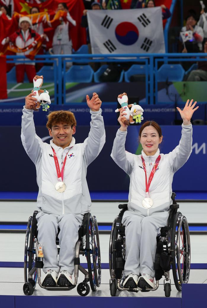백혜진(오른쪽)과 이용석이 11일(현지시간) 이탈리아 코르티나 올림픽 컬링 스타디움에서 열린 2026 밀라노·코르티나담페초 동계 패럴림픽 휠체어컬링 믹스더블 시상식에서 은메달을 걸고 기뻐하고 있다. 연합뉴스