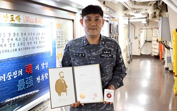 해군기동함대 충무공이순신함 류주형 원사가 헌혈 100회 달성 포장증을 들고 기념사진을 찍고 있다.