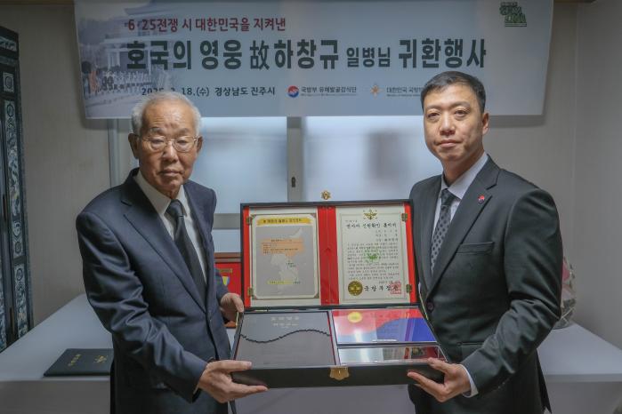 김성환(오른쪽) 국방부유해발굴감식단장 직무대리가 고 하창규 일병의 호국영웅 귀환 행사에서 고인의 아들에게 호국의 얼 함을 전달하고 있다. 부대 제공