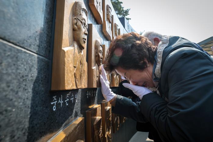 유가족이 동판을 어루만지며 눈시울을 적시고 있다.