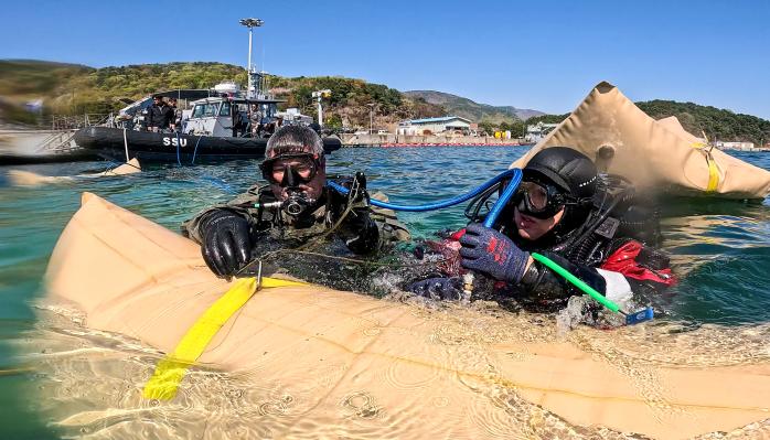 8일 경남 진해만 일대에서 진행된 연합구조전훈련에서 한국·호주 해군 잠수사들이 모의 침몰 선박 인양을 위해 리프팅백에 공기를 주입하고 있다.
