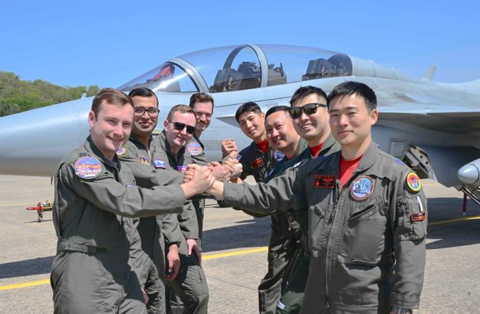 공군52시험평가전대와 미 공군 시험비행학교 조종사들이 FA-50 항공기 앞에서 손을 맞잡고 기념촬영을 하고 있다. 공군 제공