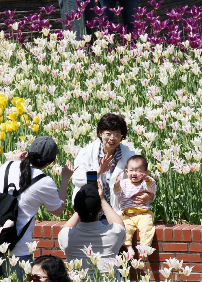 웃음꽃 활짝 낮 최고기온이 25도 안팎의 초여름 날씨를 보인 26일 경기 고양시 일산호수공원에서 열린 제18회 고양국제꽃박람회에서 나들이 나온 가족이 꽃을 배경으로 기념촬영을 하며 즐거운 시간을 보내고 있다. 연합뉴스