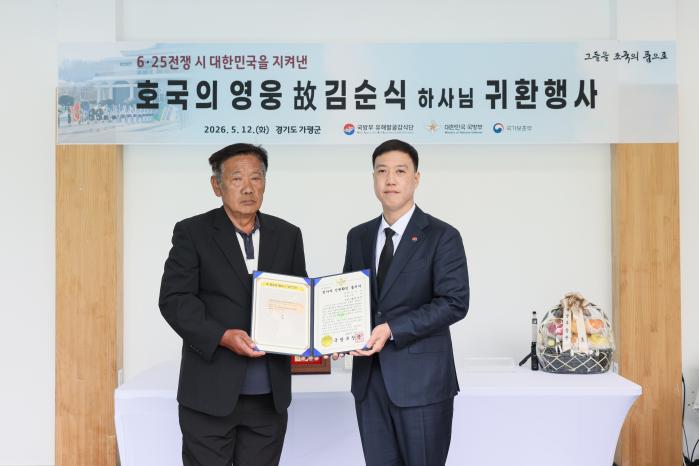 김성환(오른쪽) 국방부 유해발굴감식단장 직무대리가 12일 ‘호국의 영웅 귀환 행사’에서 고 김순식 하사의 아들 김의영 씨에게 전사자 신원확인 통지서를 전달하고 있다. 부대 제공