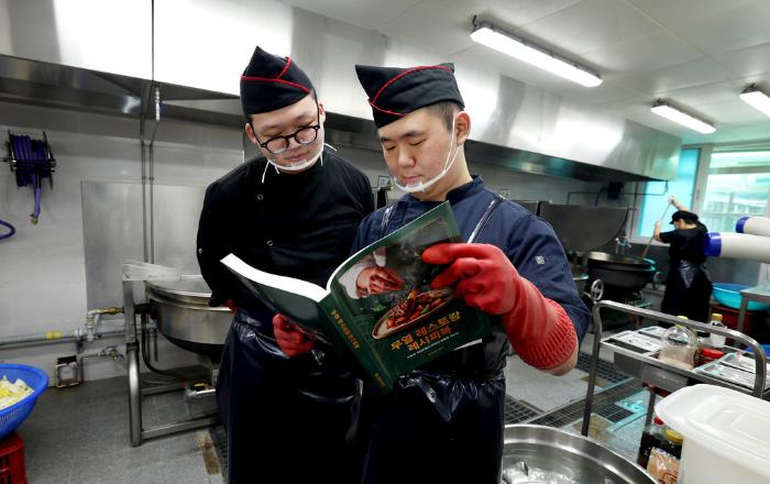 조리병들이 2작전사에서 제작한 『무열 레스토랑 레시피북』을 보고 있다.