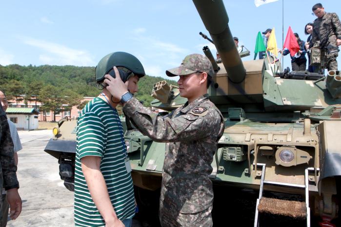 육군102기갑여단 불사조대대 장병이 지난 22일 개최된 부대개방행사 참가자의 헬멧 착용을 돕고 있다. 부대 제공