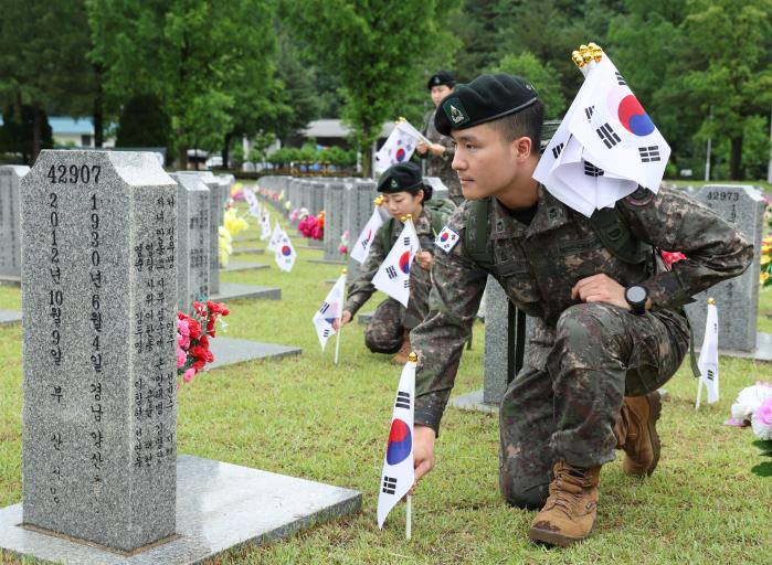 국방정신전력원 교육생들이 27일 국립대전현충원에서 순국선열·호국영웅을 참배한 뒤 묘비에 태극기를 꽂아드리고 있다. 부대 제공