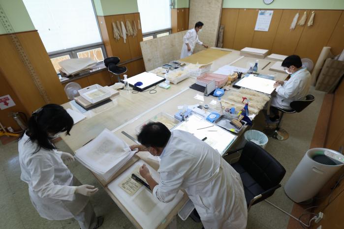 문화유산 보존처리연구원들이 6·25전쟁 군사기록물 복원작업을 하는 모습.