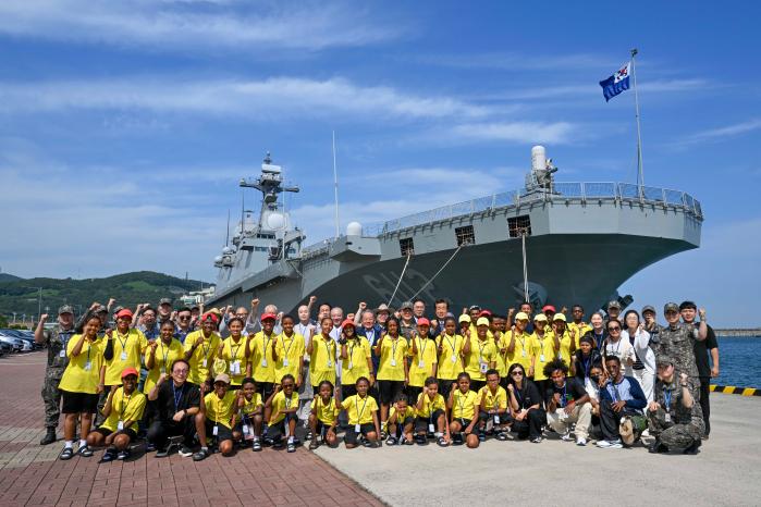 부산해군기지에 정박한 1만4500톤급 대형수송함(LPH) 마라도함을 배경으로 강뉴합창단과 해군작전사령부 장병들이 기념사진을 찍고 있다. 부대 제공