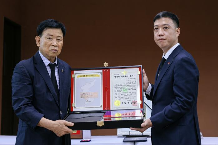 29일 열린 고 강대언 경사 ‘호국의 영웅 귀환’ 행사에서 김성환(오른쪽) 국방부 유해발굴감식단장 직무대리가 고인의 동생 강대유 옹에게 호국의 얼 함을 전달하고 있다. 국방부 제공