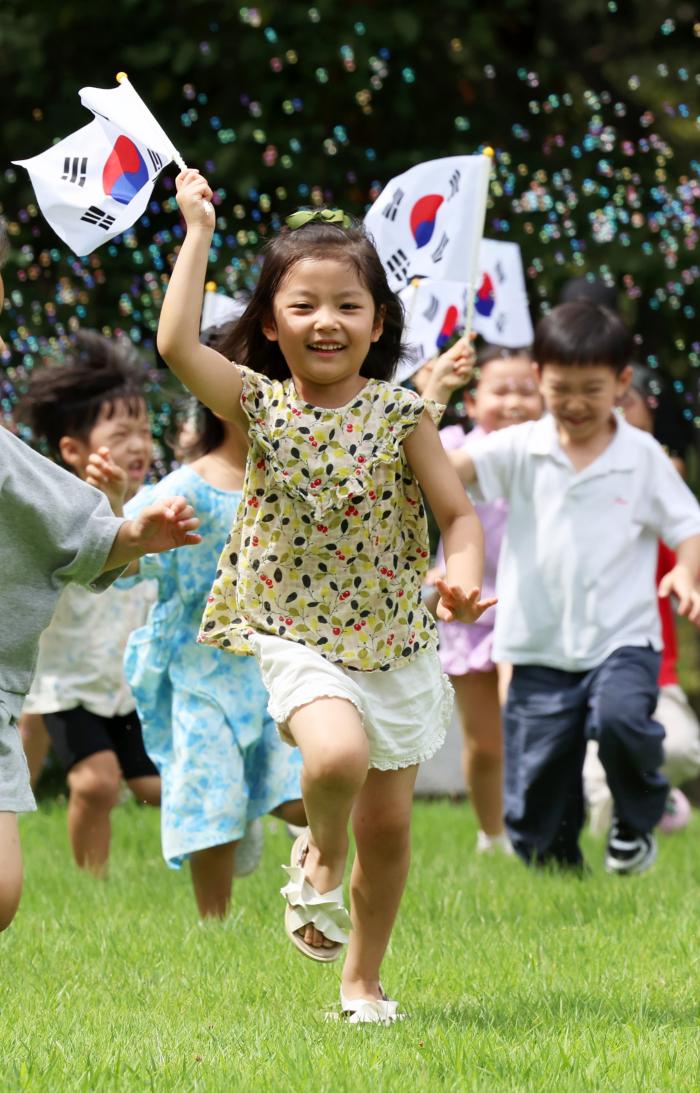 광복절을 이틀 앞둔 13일 전남광주통합특별시 북구 전남대학교 민주마루 앞에서 북구청어린이집 아이들이 야외활동하며 태극기를 흔들고 있다. 연합뉴스