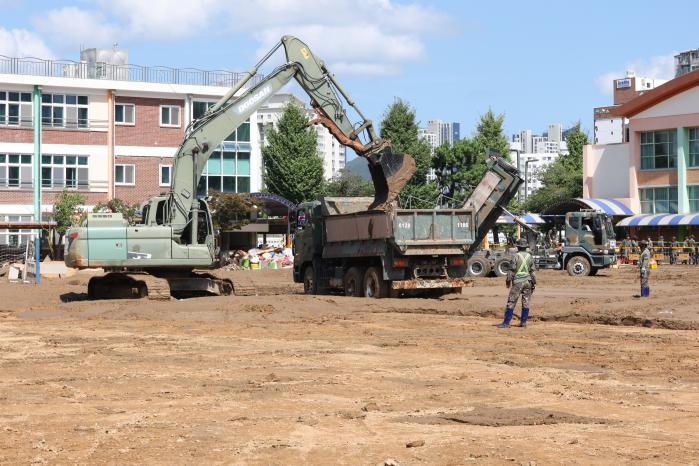 육군39보병사단 장병들이 19일 폭우로 피해를 본 경남 거제시 장평초등학교에서 굴삭기로 퍼낸 토사를 트럭에 싣고 있다.