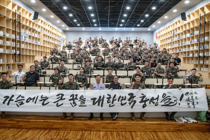 황우연 작가가 선물한 ‘가슴에는 큰 꿈을 대한민국 충성을!’ 서예 작품을 배경으로 육군부사관학교 장병들이 기념촬영을 하고 있다. 이 문구는 부사관학교 구호이기도 하다.부대 제공