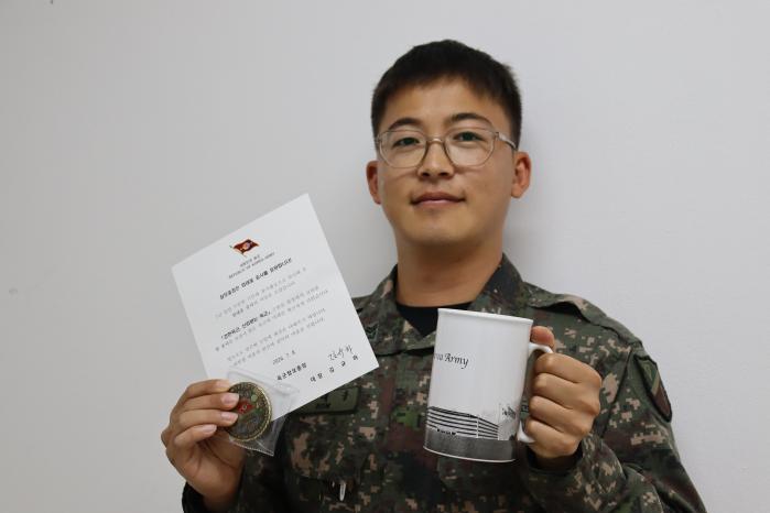 육군17보병사단 북진여단 엄대웅 중사가 육군참모총장 서신과 기념품을 들고 포즈를 취하고 있다.